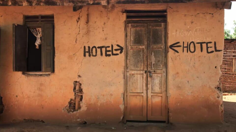 A weathered building with hand-painted "HOTEL" signs pointing in opposite directions